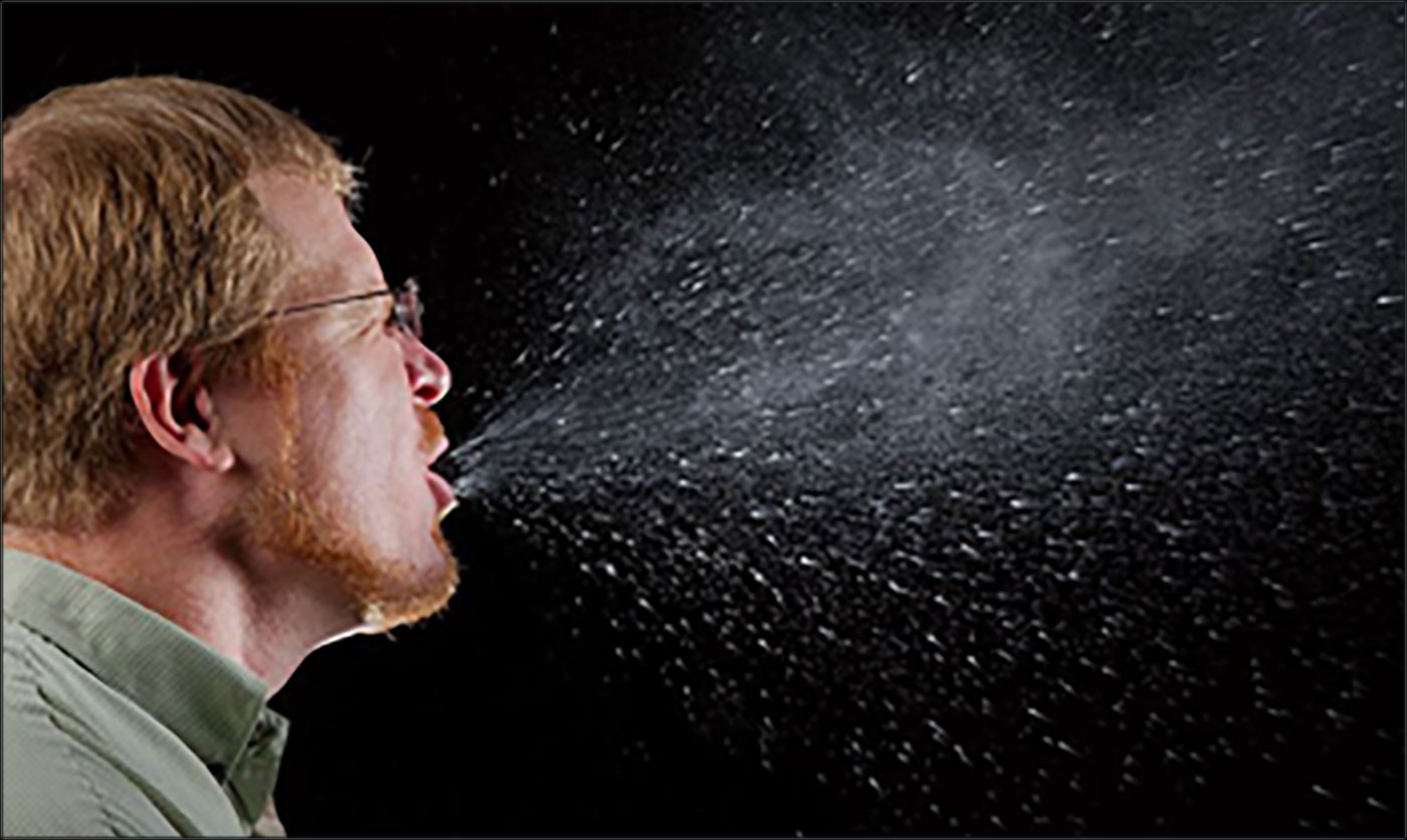 Respiratory particles being spewed from a person's mouth as they sneeze.