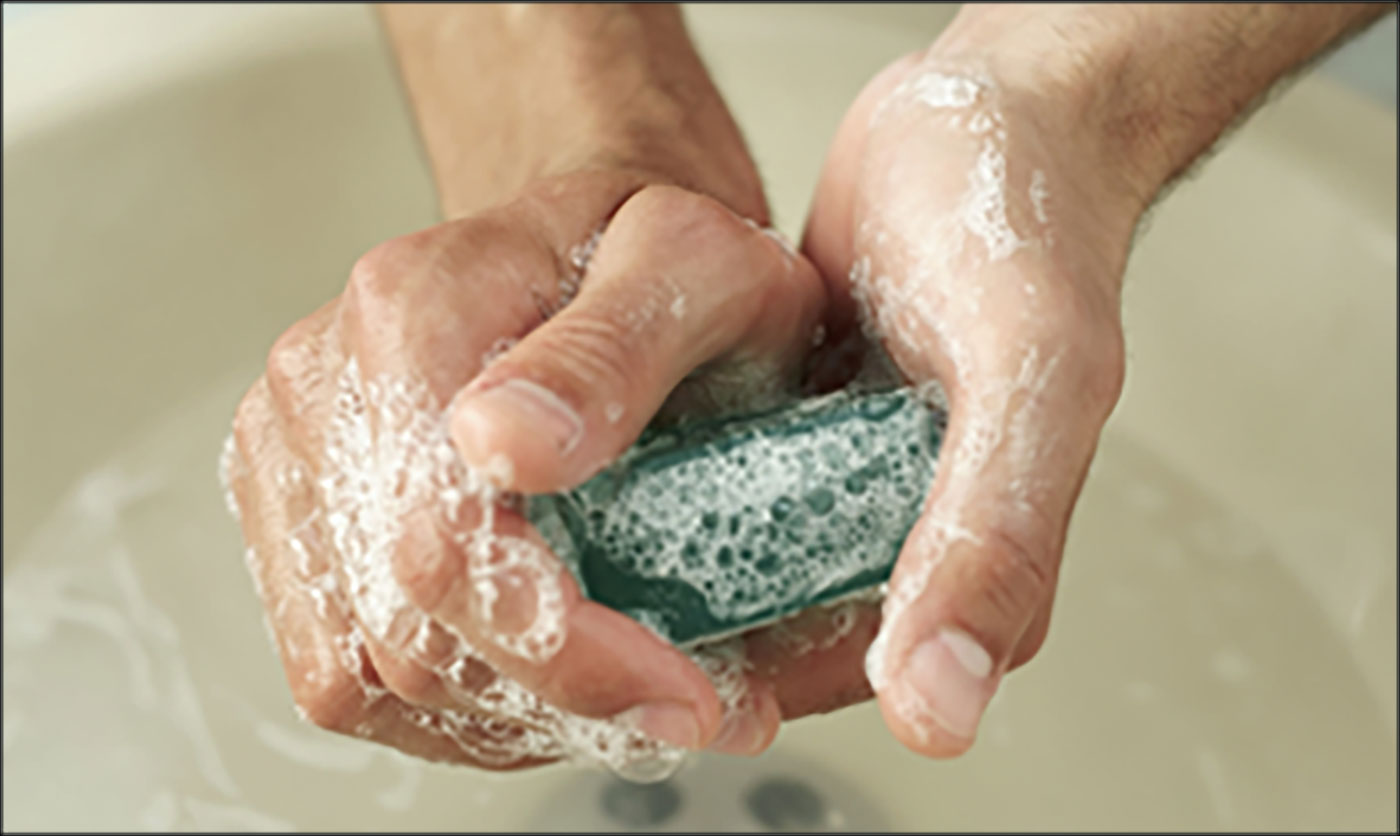 A person washing their hands over a sink.